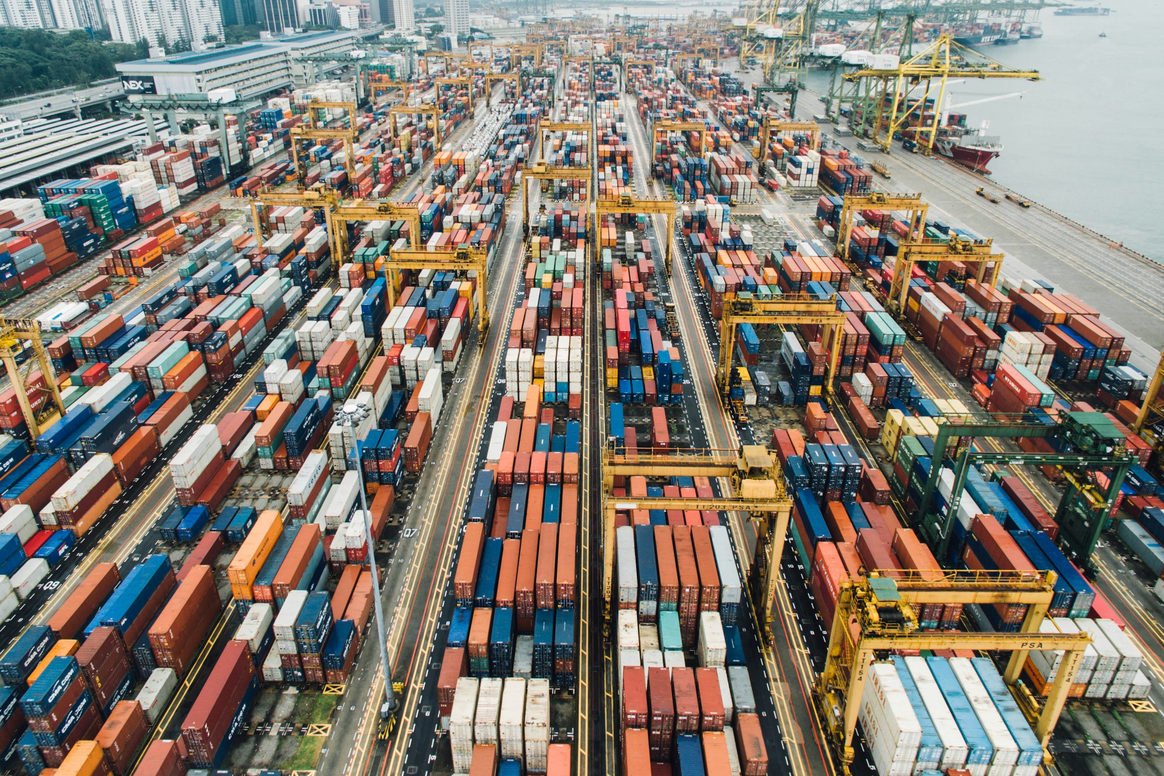 Aerial view of shipping containers and cranes at a Singapore port.